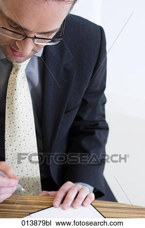 Stock Image - businessman with spectacles signing document. Fotosearch