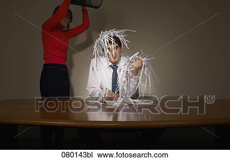 Stock Image - businesswoman emptying wastebasket over her colleague. Fotosearch