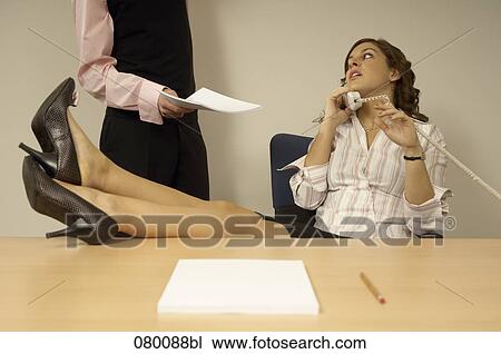 businesswoman talking on telephone with colleague disturbing her View Large Photo Image Stock Image - businesswoman talking on telephone with colleague disturbing her. Fotosearch