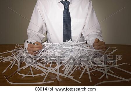 Stock Image - close-up of businessman having pile of shredded paper on his desk. Fotosearch