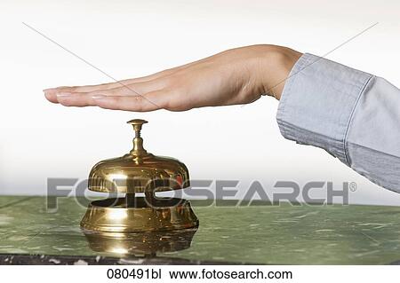 Stock Image - close-up of female hand ringing hotel reception bell. Fotosearch