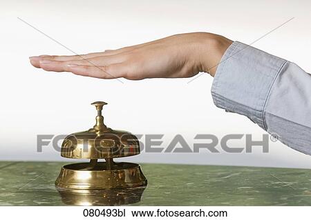 Stock Image - close-up of female hand ringing hotel reception bell. Fotosearch