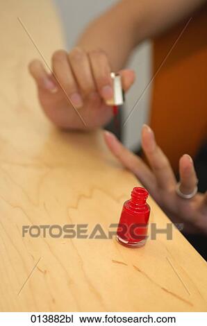 Stock Image - close-up of female office worker applying nail polish. Fotosearch