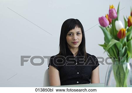 confident looking asian businesswoman sitting at table with flowers View Large Photo Image Stock Image - confident looking asian businesswoman sitting at table with flowers. Fotosearch