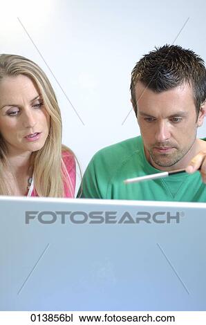 couple looking at laptop computer, man holding a pen View Large Photo Image Stock Image - couple looking at laptop computer, man holding a pen. Fotosearch