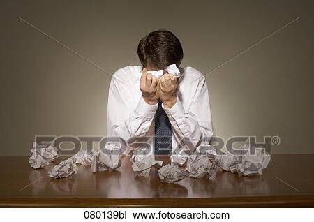 desperate businessman sitting at desk full with paper balls View Large Photo Image Stock Image - desperate businessman sitting at desk full with paper balls. Fotosearch