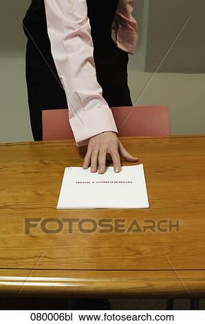 detail of businessman standing behind desk grabbing for confidential document View Large Photo Image Stock Image - detail of businessman standing behind desk grabbing for confidential document. Fotosearch