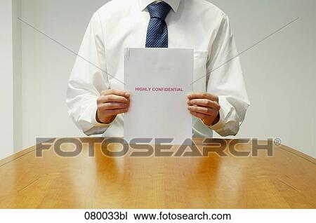 detail of executive sitting at desk holding confidential document View Large Photo Image Stock Image - detail of executive sitting at desk holding confidential document. Fotosearch