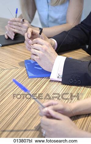 Stock Image - detail of three people´s hands with pens during business meeting. Fotosearch