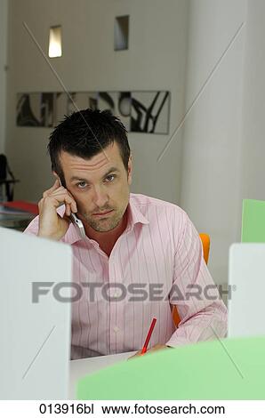 executive with cell phone sitting at desk looking at camera View Large Photo Image Stock Image - executive with cell phone sitting at desk looking at camera. Fotosearch