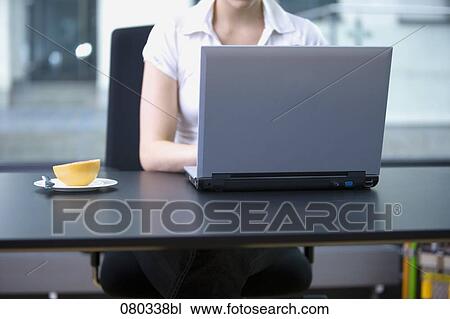 female employee working with laptop computer grapefruit on plate beside her View Large Photo Image Stock Image - female employee working with laptop computer grapefruit on plate beside her. Fotosearch