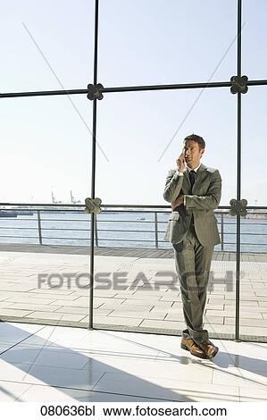 full body portrait of businessman talking on mobile phone in front of window View Large Photo Image Stock Image - full body portrait of businessman talking on mobile phone in front of window. Fotosearch