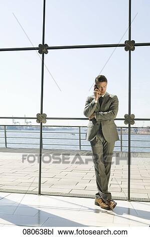 full body portrait of businessman talking on mobile phone in front of window View Large Photo Image Stock Image - full body portrait of businessman talking on mobile phone in front of window. Fotosearch