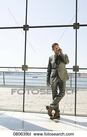full body portrait of businessman talking on mobile phone in front of window View Large Photo Image Stock Image - full body portrait of businessman talking on mobile phone in front of window. Fotosearch