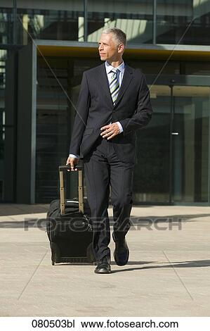Stock Image - full body portrait of mature businessman with carry-on suitcase. Fotosearch