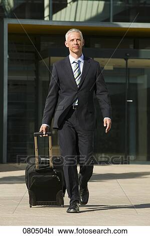 Stock Image - full body portrait of mature businessman with carry-on suitcase. Fotosearch