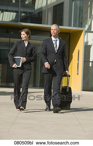 Stock Image - full body portrait of mature businesswoman and businessman leaving office building. Fotosearch