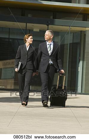 Stock Image - full body portrait of mature businesswoman and businessman leaving office building. Fotosearch