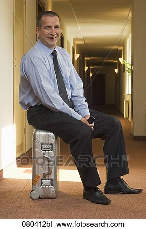 full body portrait of smiling mature businessman sitting on suitcase in hotel corridor View Large Photo Image Stock Image - full body portrait of smiling mature businessman sitting on suitcase in hotel corridor. Fotosearch