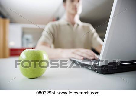 green apple on desk with businessman working on laptop computer View Large Photo Image Stock Image - green apple on desk with businessman working on laptop computer. Fotosearch