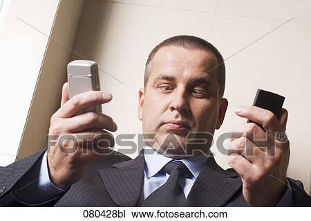 headshot of cross-eyed mature businessman with two mobile phones View Large Photo Image Stock Image - headshot of cross-eyed mature businessman with two mobile phones. Fotosearch