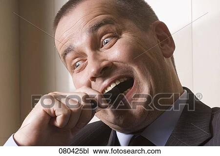 headshot of desperate businessman biting into mobile phone View Large Photo Image Stock Image - headshot of desperate businessman biting into mobile phone. Fotosearch
