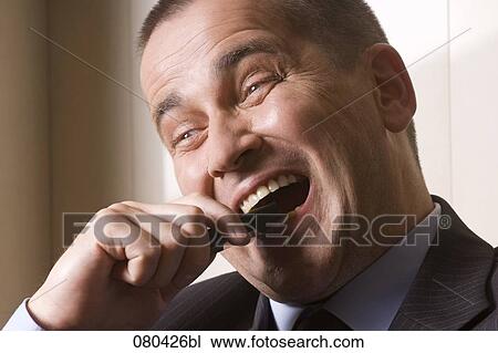 headshot of desperate businessman biting into mobile phone View Large Photo Image Stock Image - headshot of desperate businessman biting into mobile phone. Fotosearch
