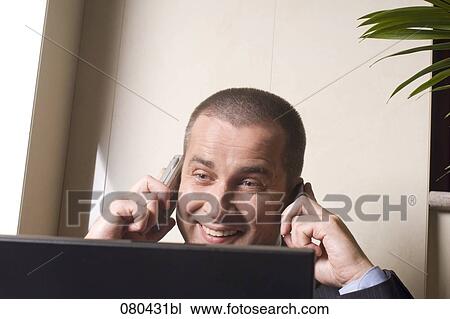 headshot of mature businessman listening to two mobile phones at once and looking at screen of laptop computer View Large Photo Image Stock Image - headshot of mature businessman listening to two mobile phones at once and looking at screen of laptop computer. Fotosearch