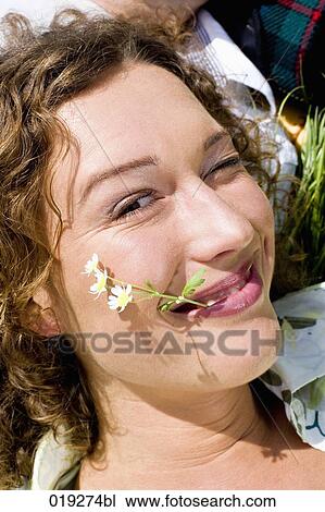headshot of winking young woman with flower in mouth View Large Photo Image Stock Image - headshot of winking young woman with flower in mouth. Fotosearch