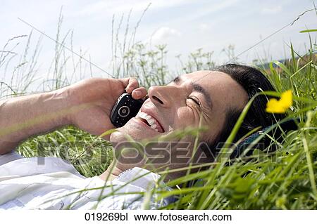 headshot of young man lying in grass talking on mobile phone View Large Photo Image Stock Image - headshot of young man lying in grass talking on mobile phone. Fotosearch