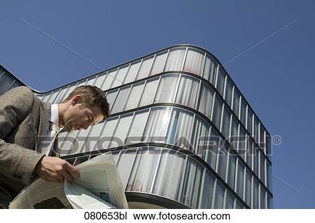 low angle portrait of businessman reading newspaper in front of office building View Large Photo Image Stock Image - low angle portrait of businessman reading newspaper in front of office building. Fotosearch