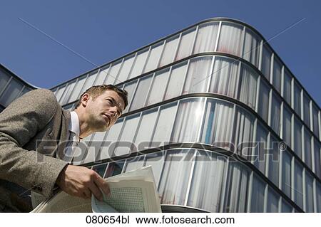 low angle portrait of businessman reading newspaper in front of office building View Large Photo Image Stock Image - low angle portrait of businessman reading newspaper in front of office building. Fotosearch