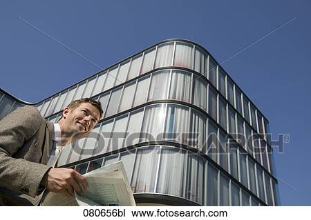 low angle portrait of businessman reading newspaper in front of office building View Large Photo Image Stock Image - low angle portrait of businessman reading newspaper in front of office building. Fotosearch