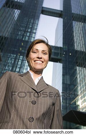 Stock Image - low angle portrait of smiling mature businesswoman in front of office building. Fotosearch