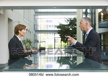 Stock Image - mature businessman talking to female employee at reception. Fotosearch