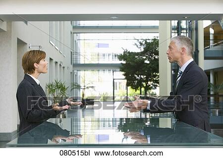 Stock Image - mature businessman talking to female employee at reception. Fotosearch