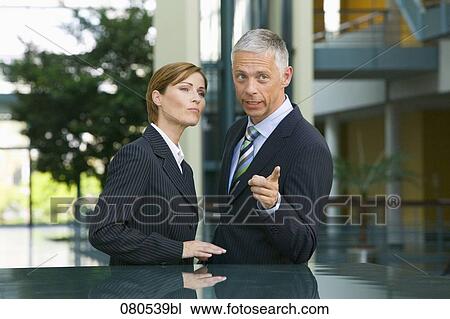 mature businesswoman and male colleague having conversation in office lobby View Large Photo Image Stock Image - mature businesswoman and male colleague having conversation in office lobby. Fotosearch