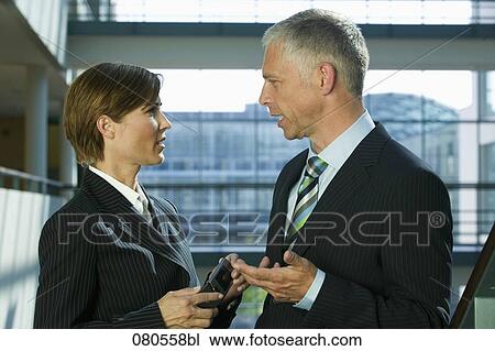 Stock Image - mature businesswoman and male colleague having a conversation. Fotosearch