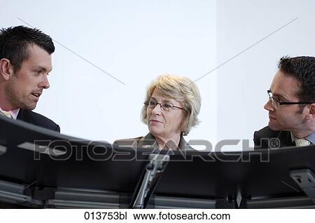 Stock Image - mature businesswoman and two male colleagues having a meeting. Fotosearch