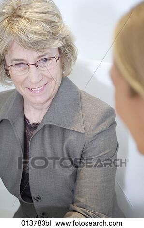 mature businesswoman having conversation with colleague View Large Photo Image Stock Image - mature businesswoman having conversation with colleague. Fotosearch
