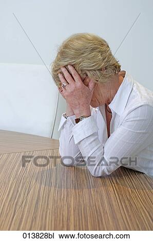 mature businesswoman sitting at table covering her face in despair View Large Photo Image Stock Image - mature businesswoman sitting at table covering her face in despair. Fotosearch