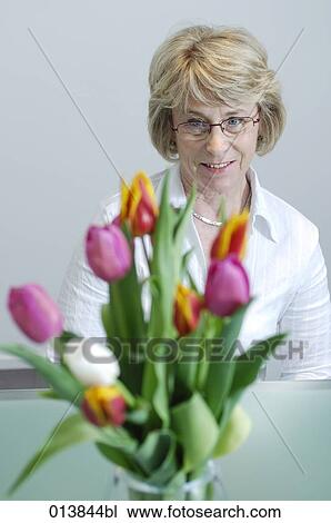 Stock Image - mature executive sitting behind flowers. Fotosearch