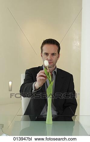 office worker sitting at table touching flower View Large Photo Image Stock Image - office worker sitting at table touching flower. Fotosearch