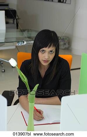 Stock Image - portrait of asian executive sitting at desk writing. Fotosearch