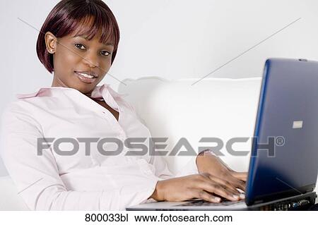 portrait of black woman sitting on sofa and working with laptop computer View Large Photo Image Stock Image - portrait of black woman sitting on sofa and working with laptop computer. Fotosearch
