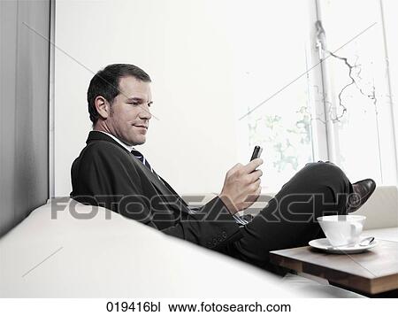Stock Image - portrait of businessman checking his mobile phone for text messages. Fotosearch