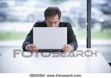 Stock Image - portrait of businessman hiding behind laptop computer. Fotosearch