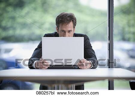 portrait of businessman hiding behind laptop computer View Large Photo Image Stock Image - portrait of businessman hiding behind laptop computer. Fotosearch