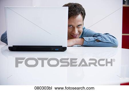 portrait of businessman peeking behind laptop computer View Large Photo Image Stock Image - portrait of businessman peeking behind laptop computer. Fotosearch