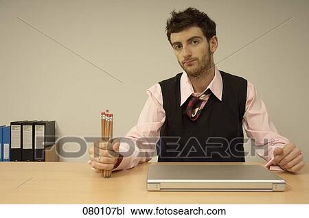 portrait of businessman sitting at desk holding pencils View Large Photo Image Stock Image - portrait of businessman sitting at desk holding pencils. Fotosearch
